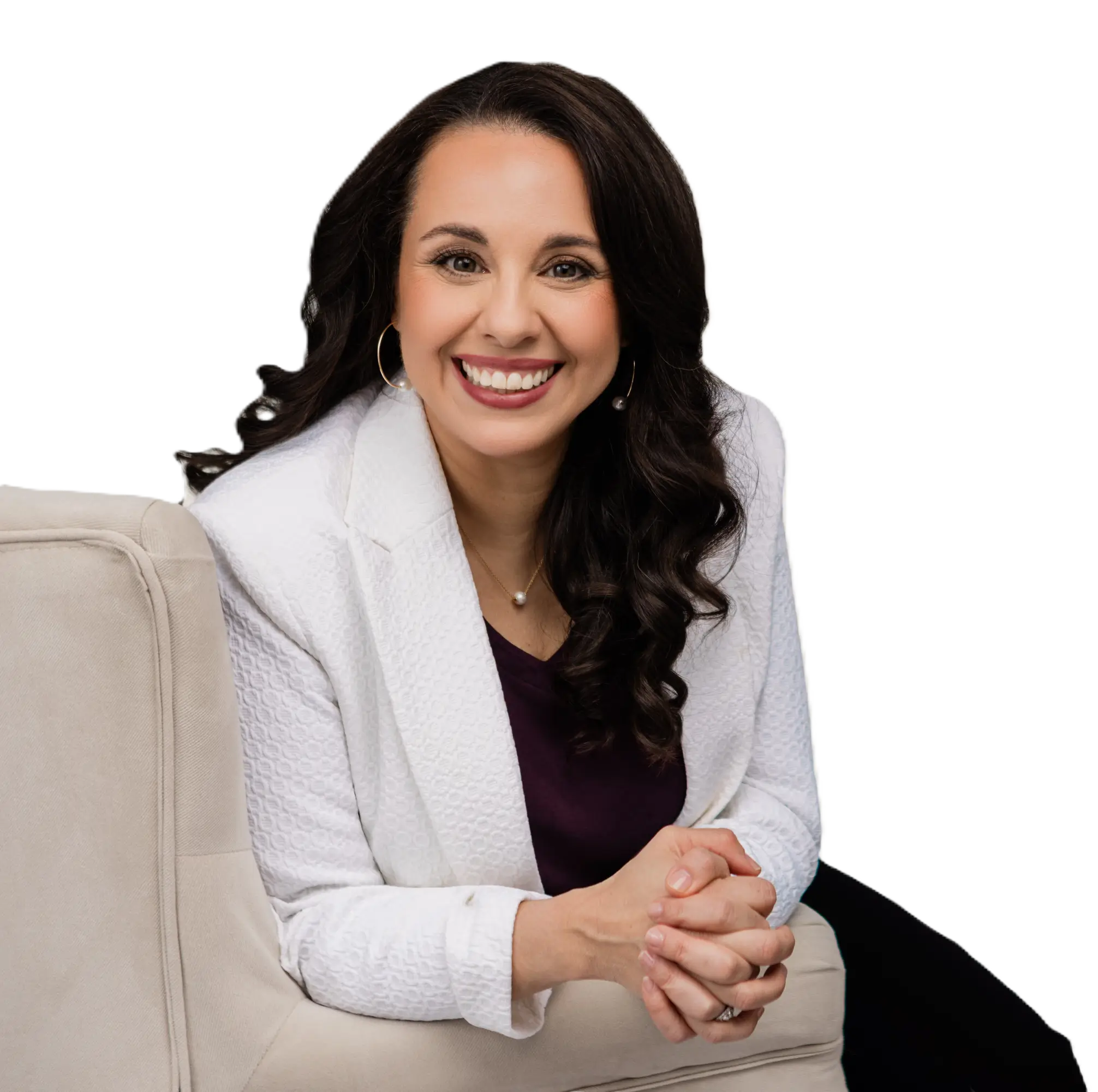 Melisa Berry sitting on armchair in black shirt and white jacket looking back at camera